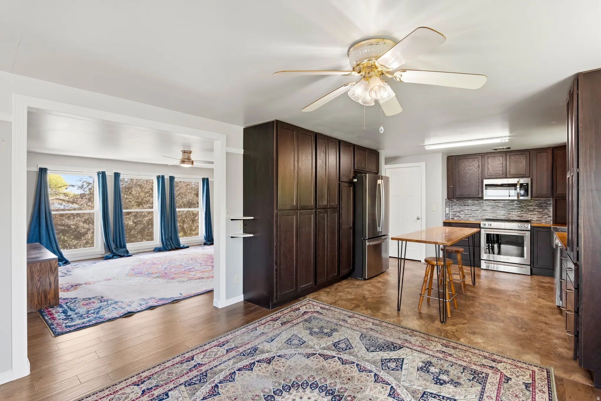 Kitchen featuring dark wood cabinetry, stainless steel appliances, and a tiled backsplash