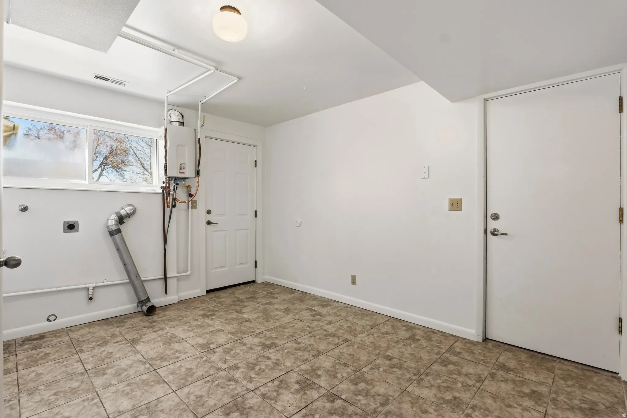 Utility room featuring tiled flooring, a window, a tankless water heater, and a flush-mount ceiling light fixture
