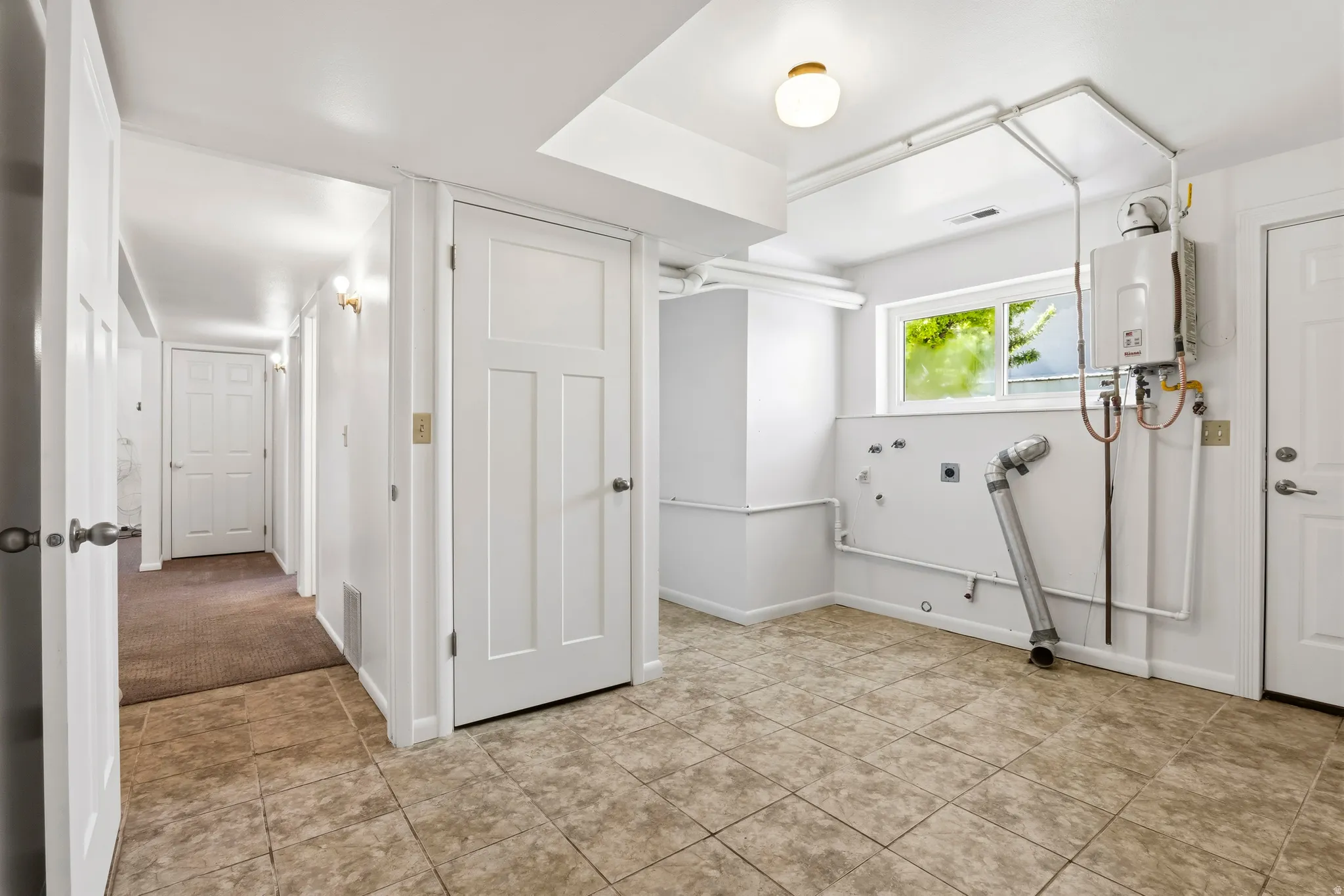 Utility area featuring tile flooring, white walls, and a window providing natural light