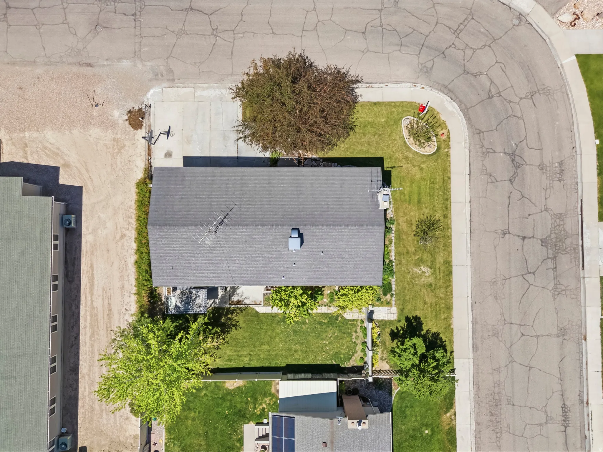 Property featuring a gray asphalt shingle roof, mature landscaping, a paved driveway, and a front lawn
