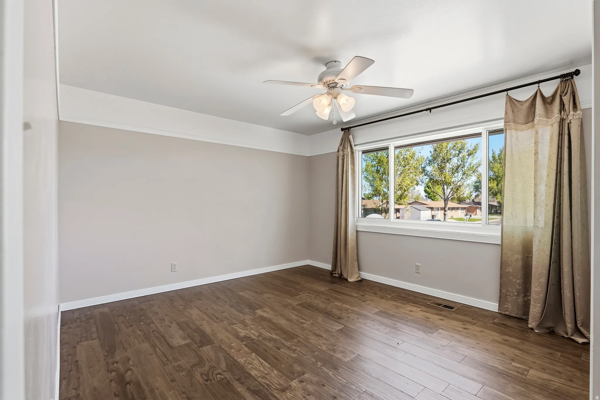 Interior space featuring wood-finish flooring, a large window with natural light, and a ceiling fan with integrated lighting