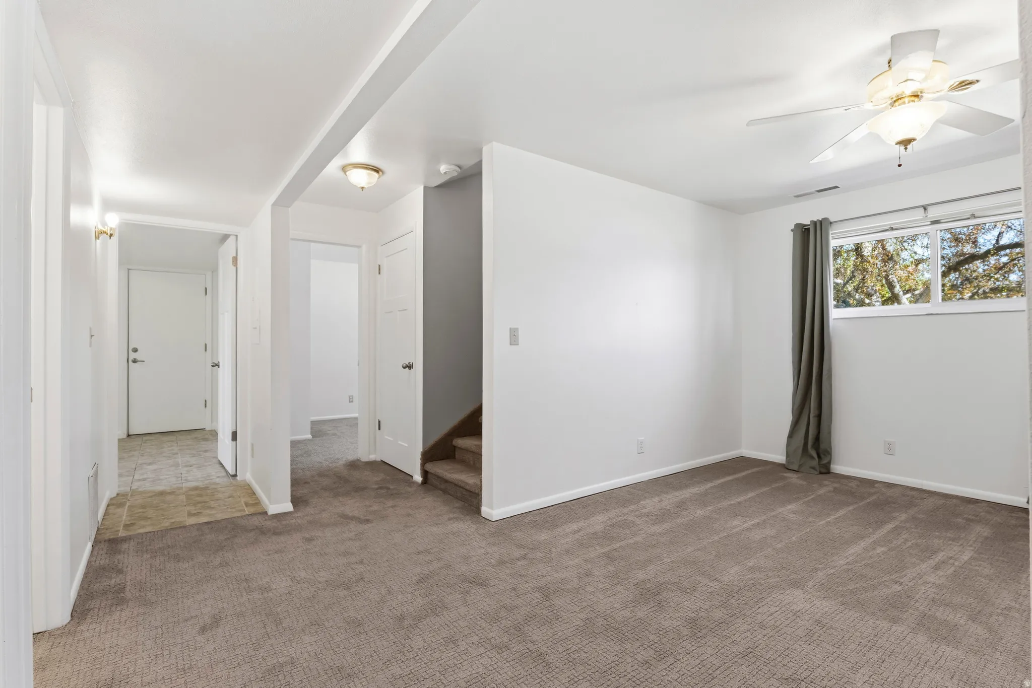 Spacious room featuring neutral carpeting, white walls, and a multi-pane window