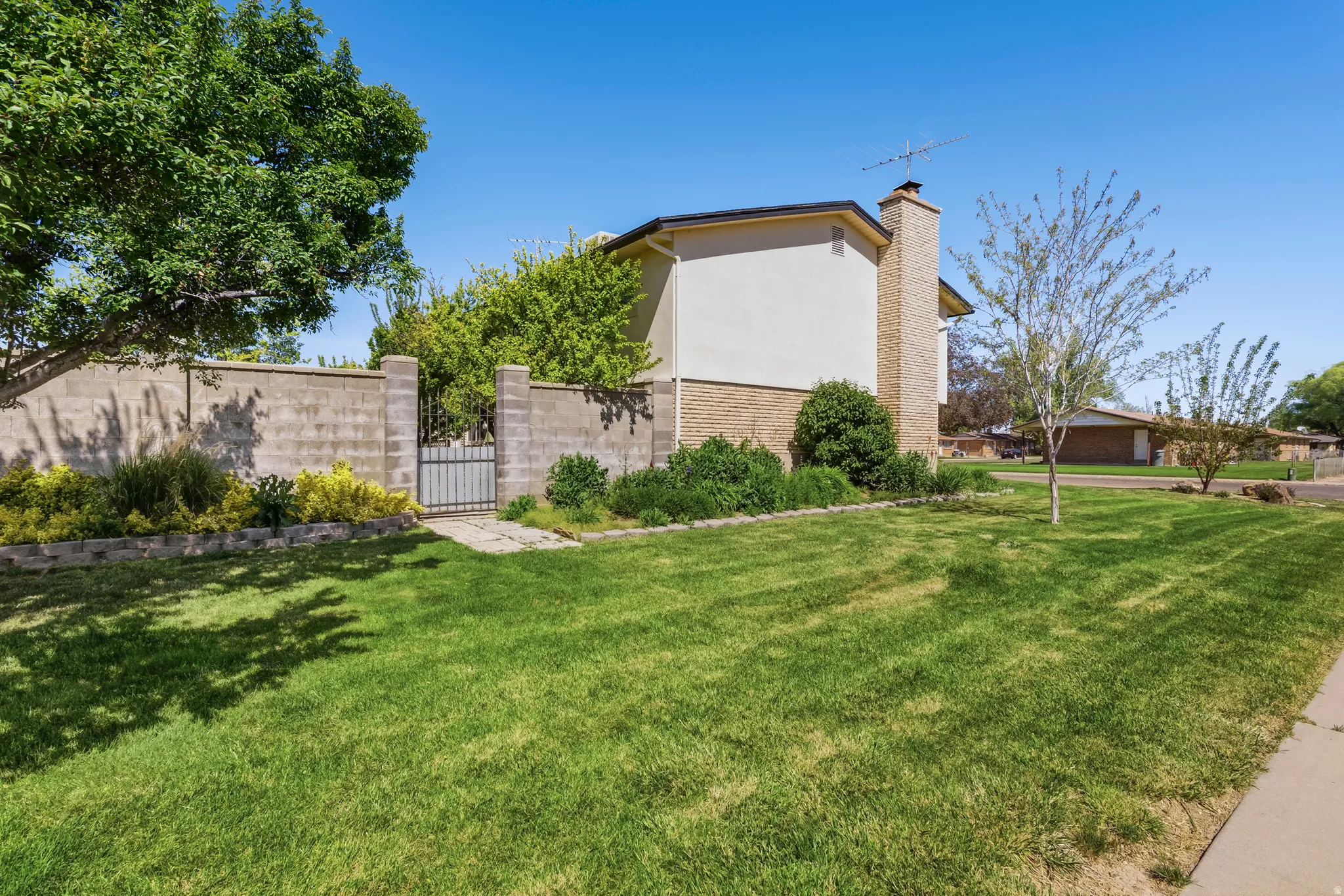 Mature landscaping with a block wall perimeter and wrought iron gate