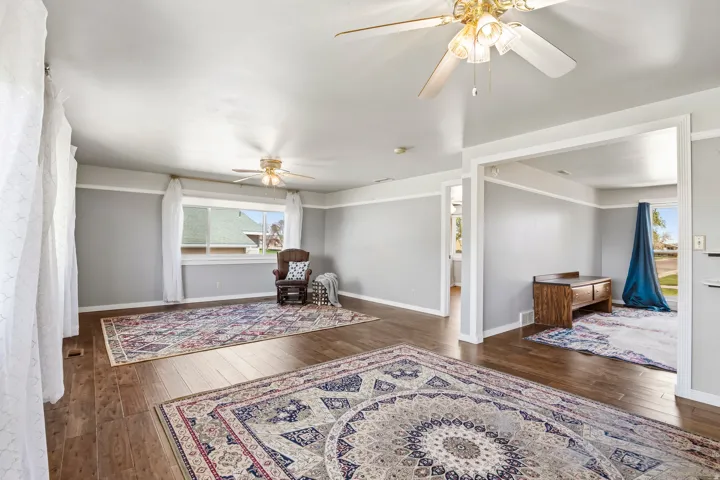 Spacious room featuring wood-finish flooring, light grey walls with white trim, and multiple windows