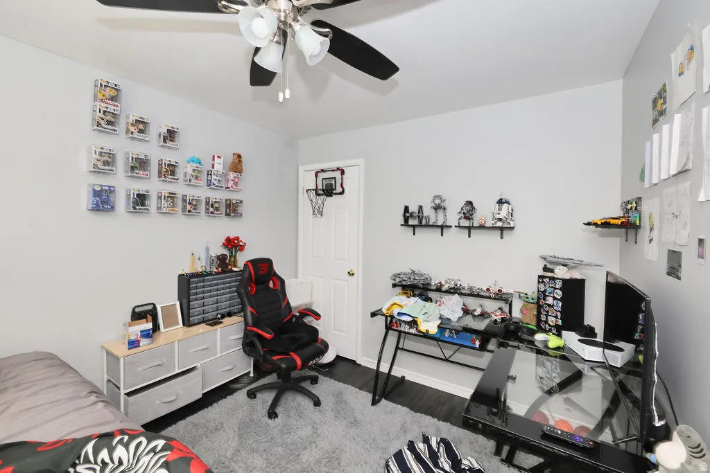 Room featuring a ceiling fan with integrated lighting, dark wood-finish flooring, and light-colored walls