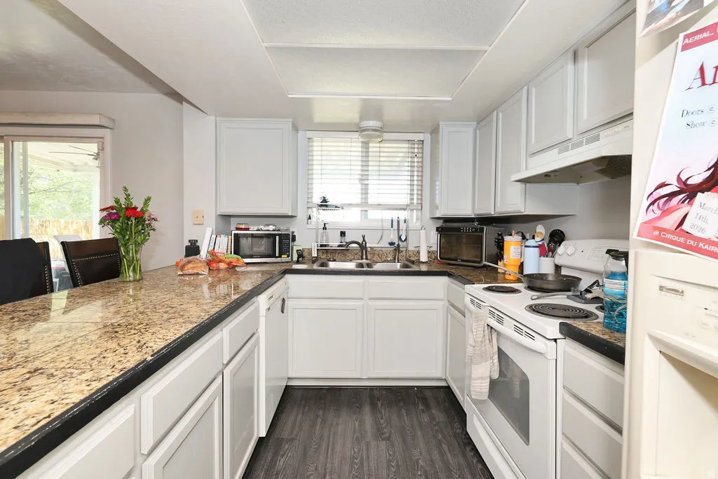 U-shaped kitchen featuring wood-finish flooring, white cabinetry, granite-finish countertops, and a full-size range