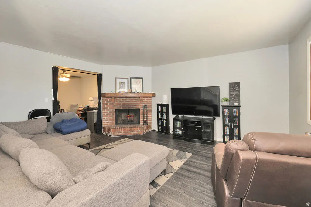 Living area featuring wood-finish flooring, a brick fireplace with a wood mantel, and light gray wall paint