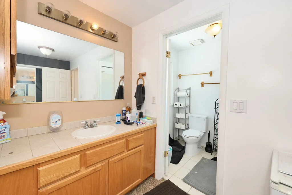 Bathroom vanity featuring a tile countertop, integrated sink, and light wood cabinetry