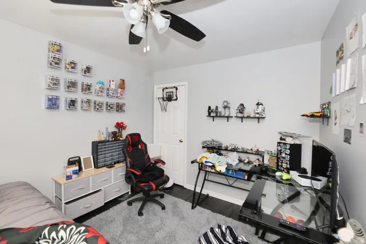 Room featuring a ceiling fan with integrated lighting, dark wood-finish flooring, and light-colored walls