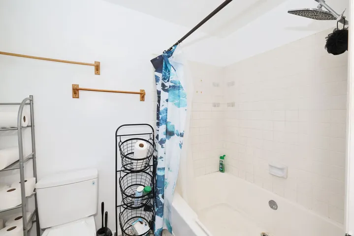 White tile-surround bathtub and shower combination with a rainfall showerhead