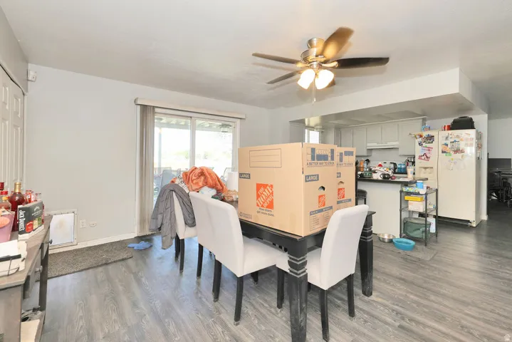 Open-concept living space featuring wood-finish flooring, a ceiling fan with integrated lighting, and a sliding glass door providing outdoor access