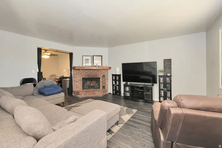 Living area featuring wood-finish flooring, a brick fireplace with a wood mantel, and light gray wall paint