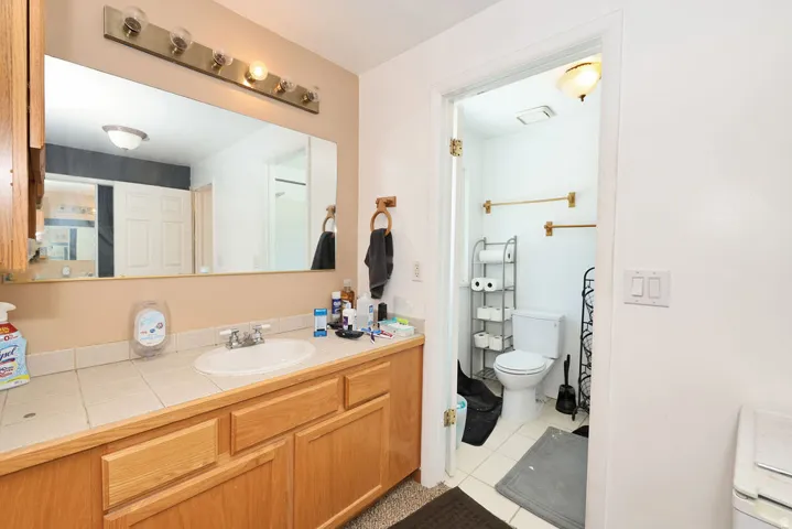 Bathroom vanity featuring a tile countertop, integrated sink, and light wood cabinetry
