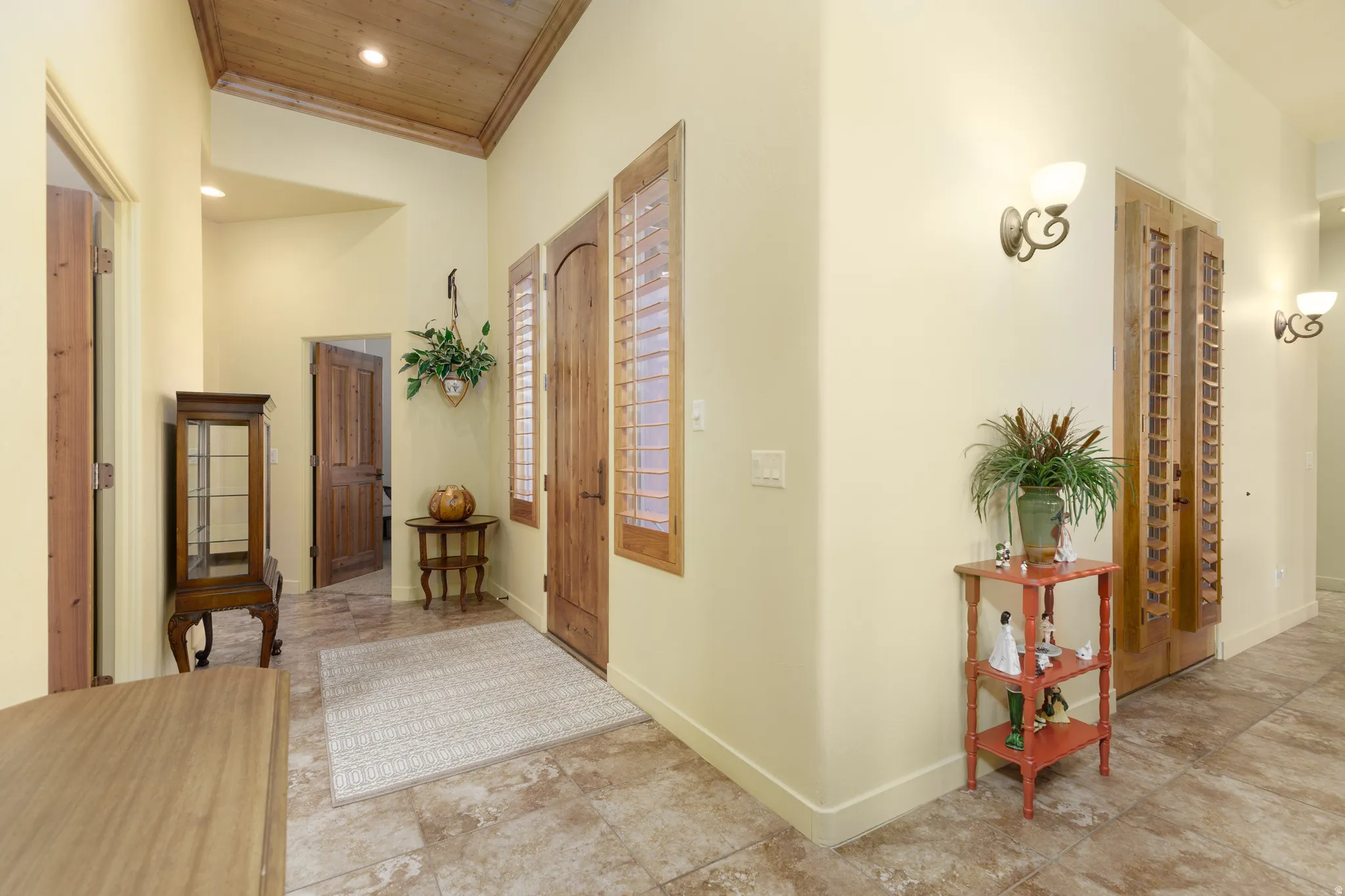 Entryway featuring wood-finish vaulted ceilings, tile flooring, and sconce lighting