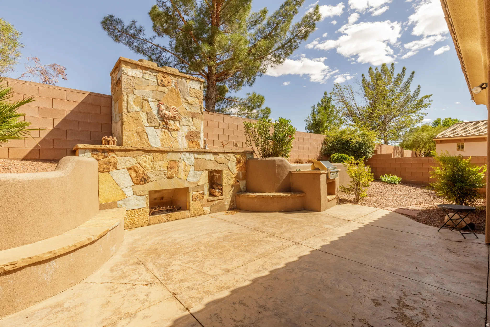Expansive patio featuring a built-in outdoor fireplace with hearth, integrated grill station, and curved stucco seating