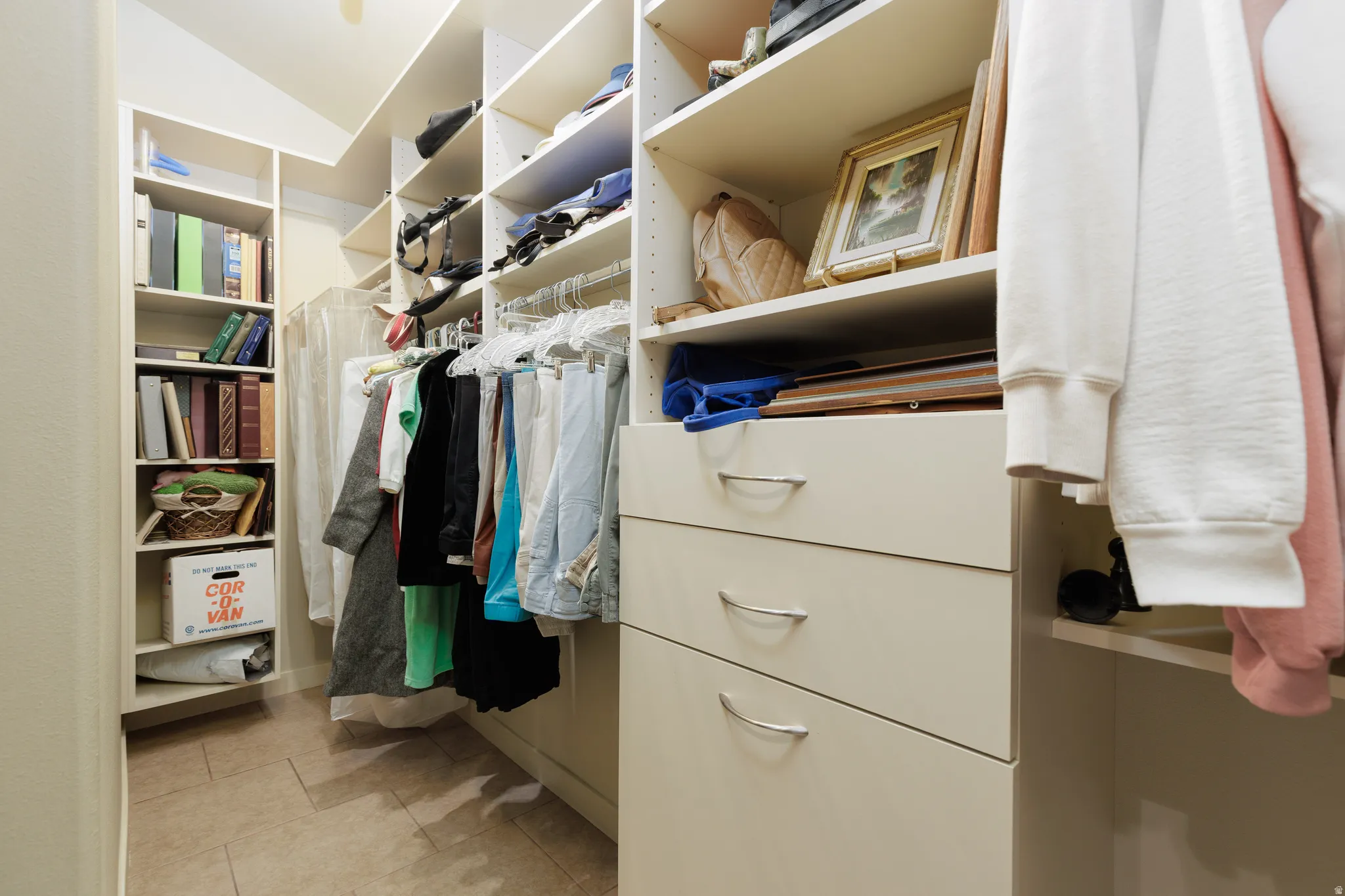 Custom closet system featuring built-in shelving, hanging rods, and integrated drawers with curved metal pulls