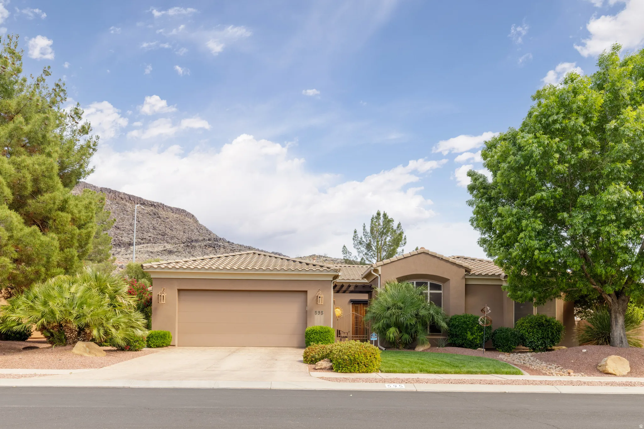 Stucco exterior residence featuring a tile roof, an integrated garage, and a concrete driveway