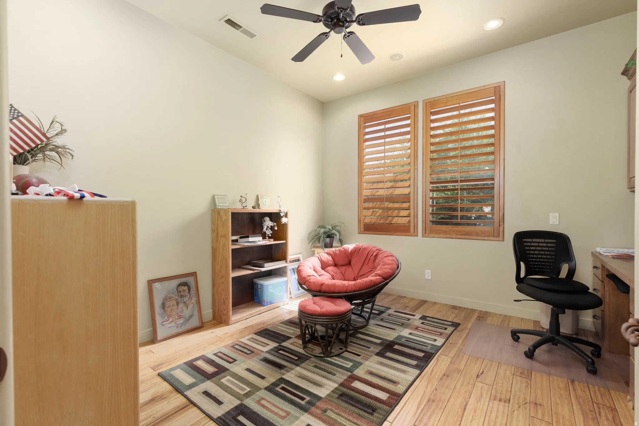 Room featuring wood-finish flooring, two windows with wooden plantation shutters, a ceiling fan, and recessed lighting