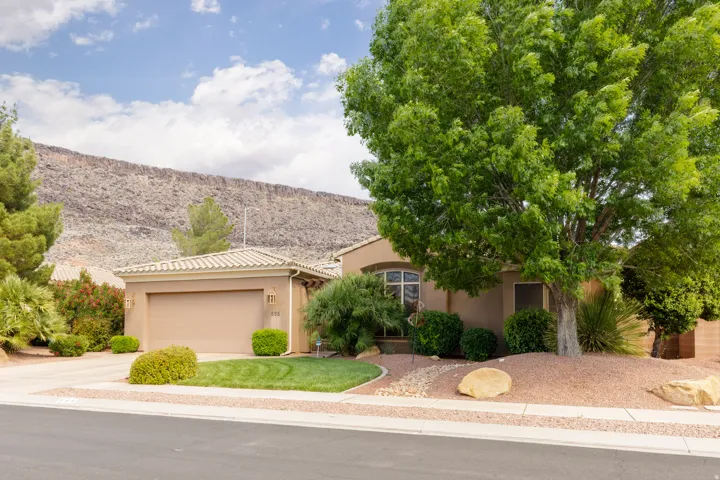 Stucco exterior residence with an attached garage, featuring a tile roof and a bay window
