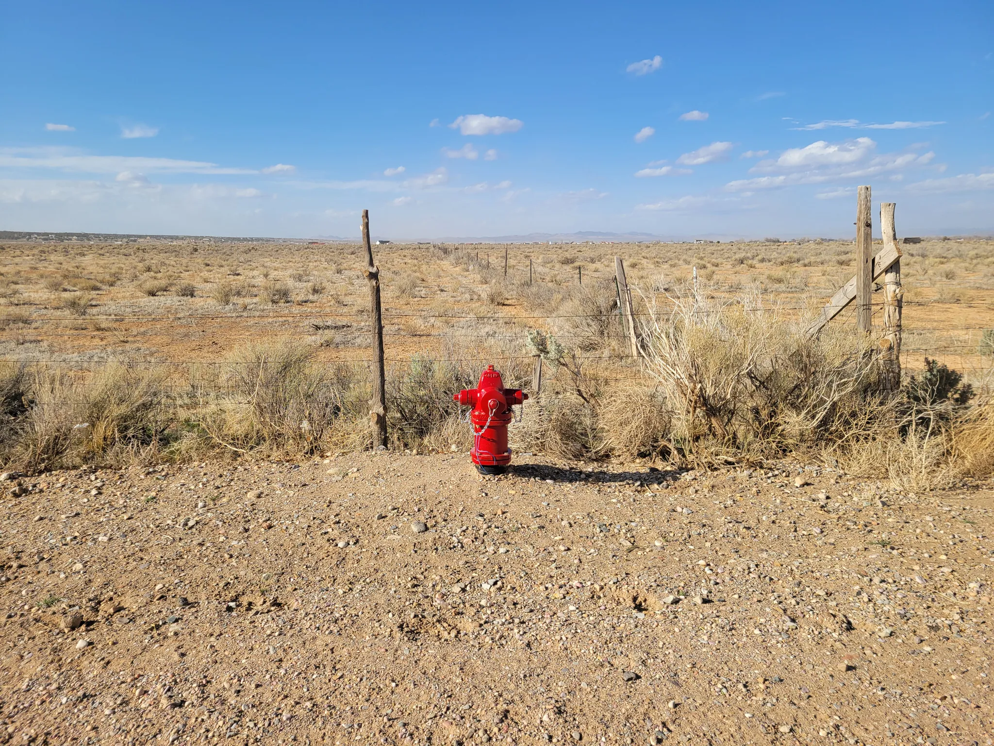 Red fire hydrant on a gravel and dirt surface