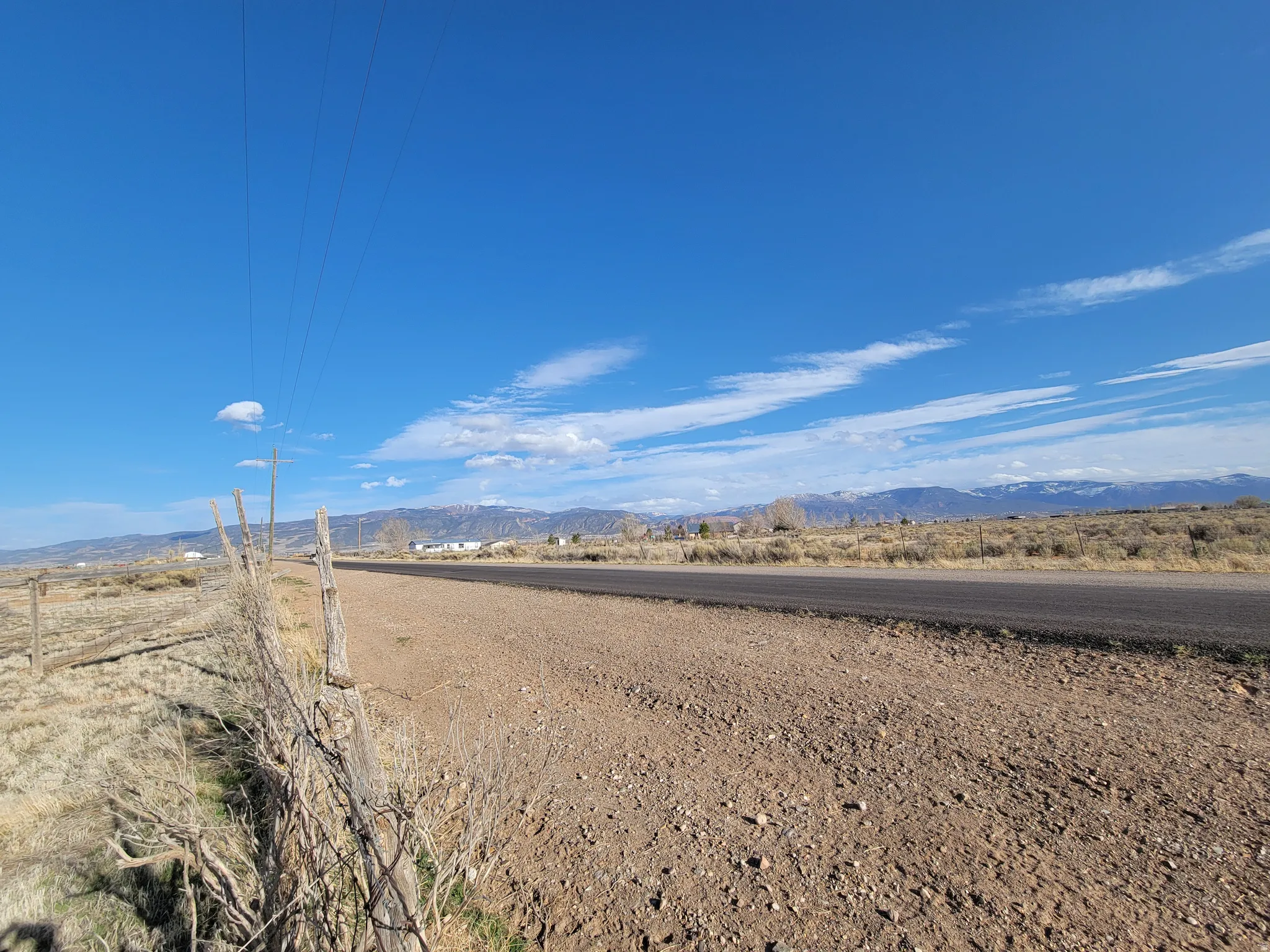 Paved road frontage with expansive arid landscape and distant snow-capped mountains