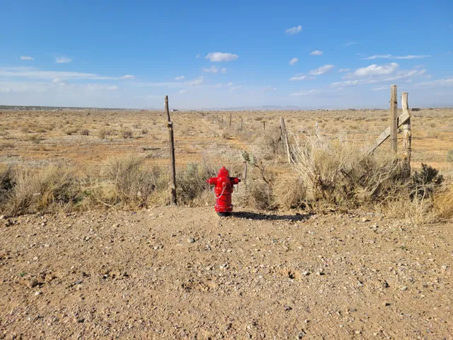 Red fire hydrant on a gravel and dirt surface