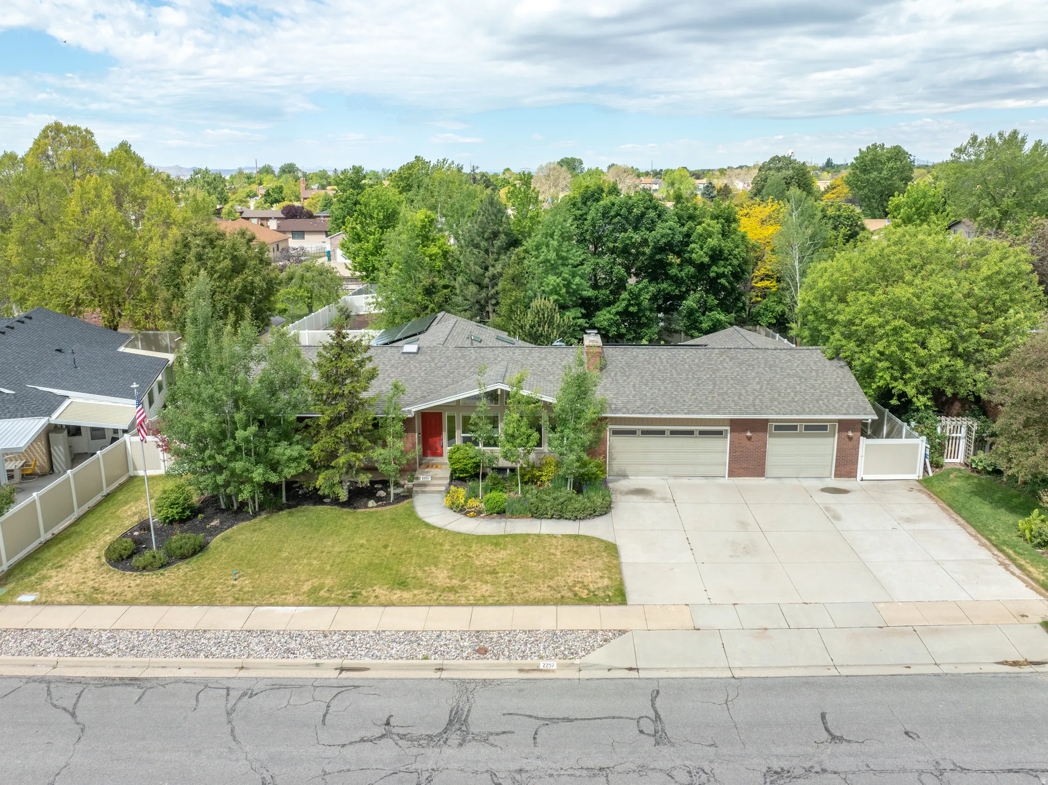 Brick-front residence featuring an attached two-car garage, a concrete driveway, and a front walk leading to a red entry door