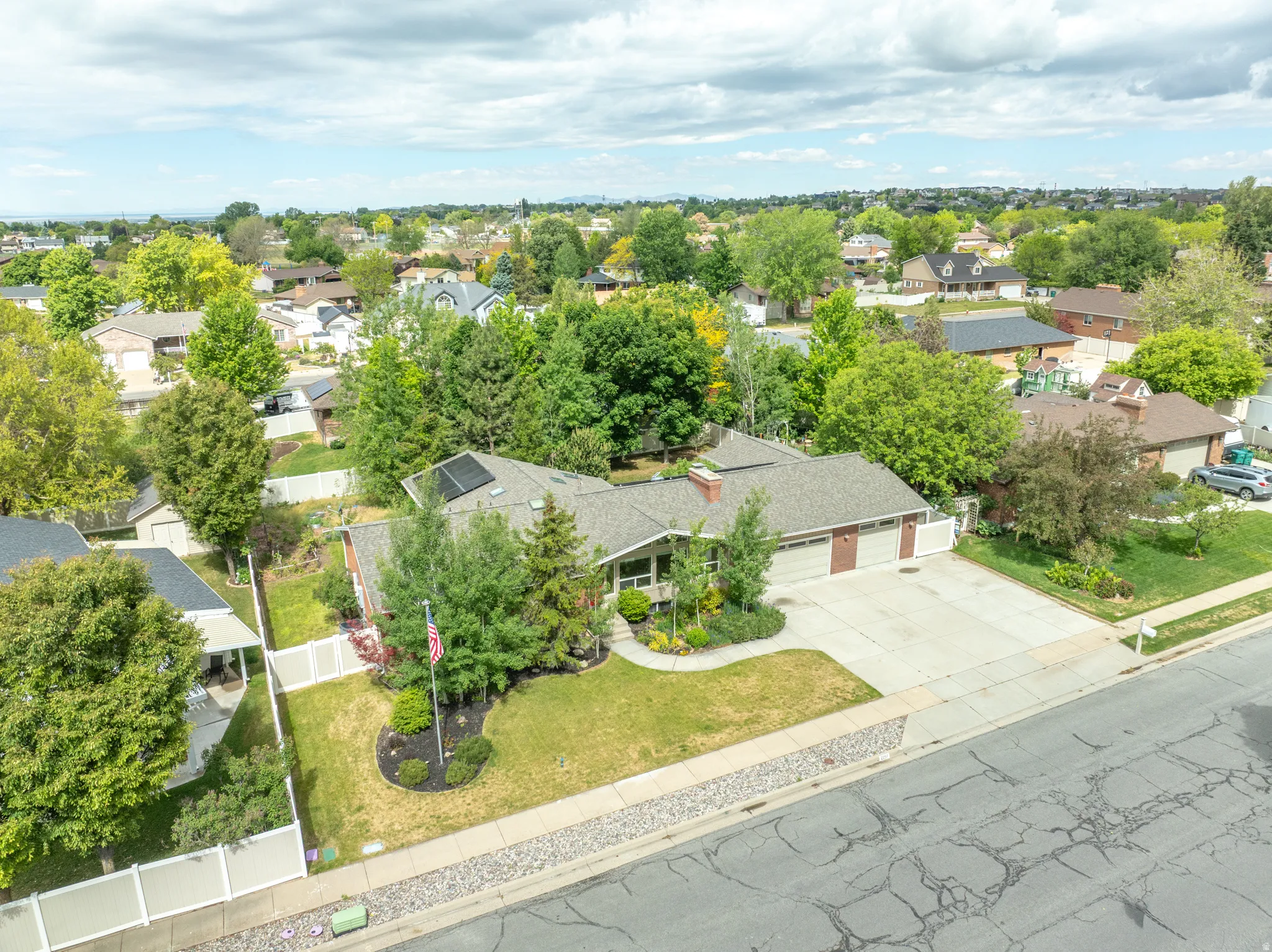 Ranch-style residence featuring a two-car garage, mature landscaping, and a paved driveway