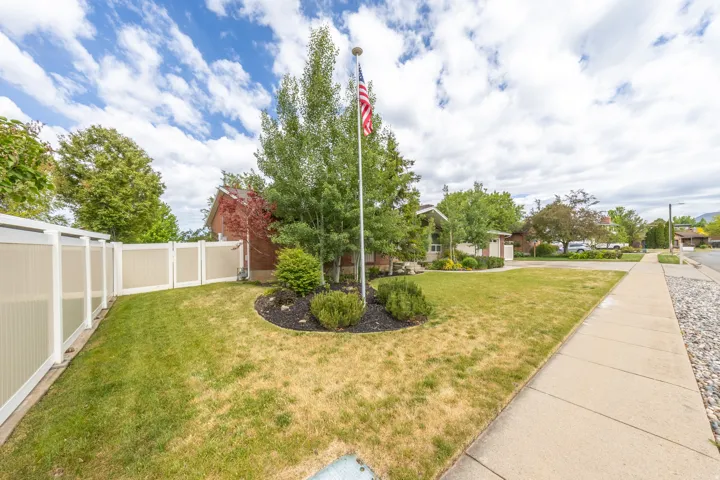 Spacious front lawn with mature trees and a flag pole feature