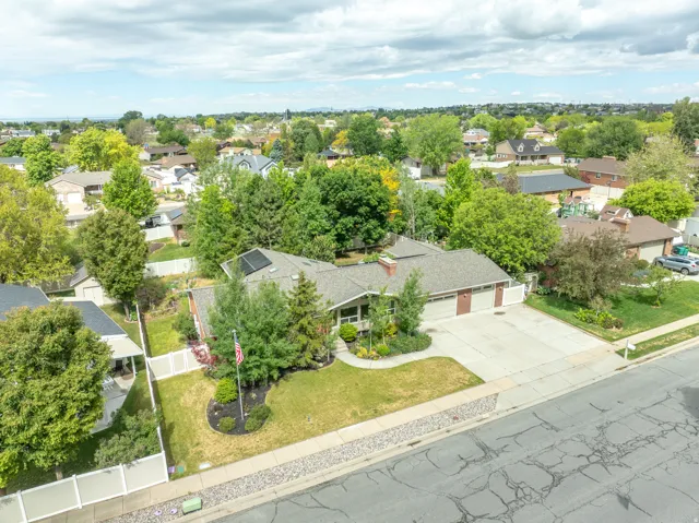 Ranch-style residence featuring a two-car garage, mature landscaping, and a paved driveway