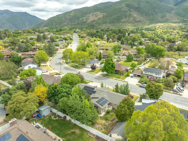 Residential neighborhood with a curved street layout, surrounded by mature trees and mountain scenery