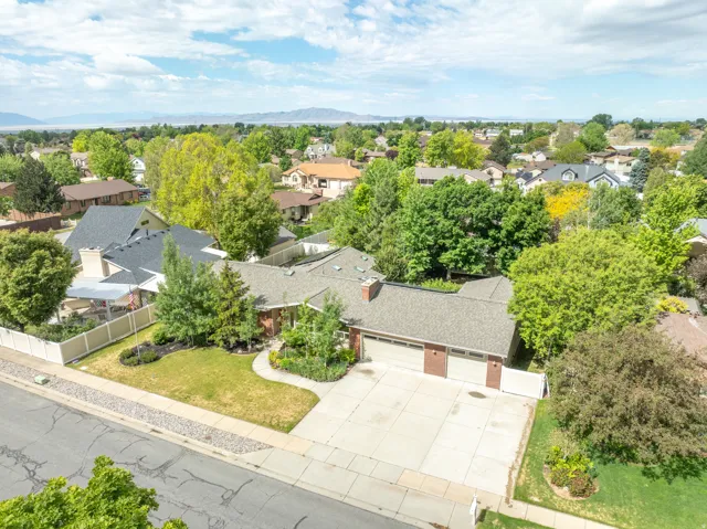 Expansive property featuring a brick facade, attached two-car garage, mature landscaping, and a substantial paved driveway