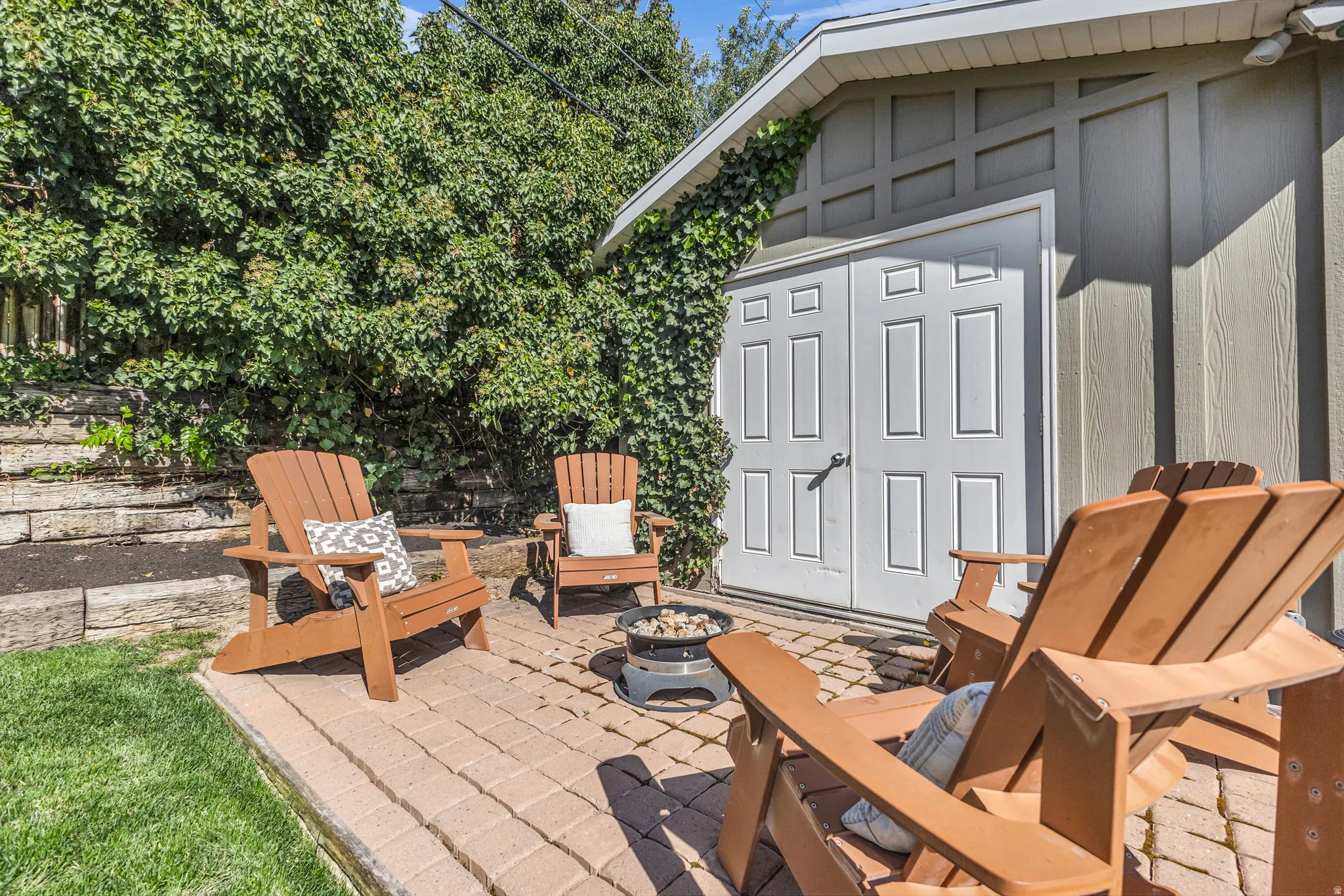 Patio area, fire pit and shed in lush landscaping