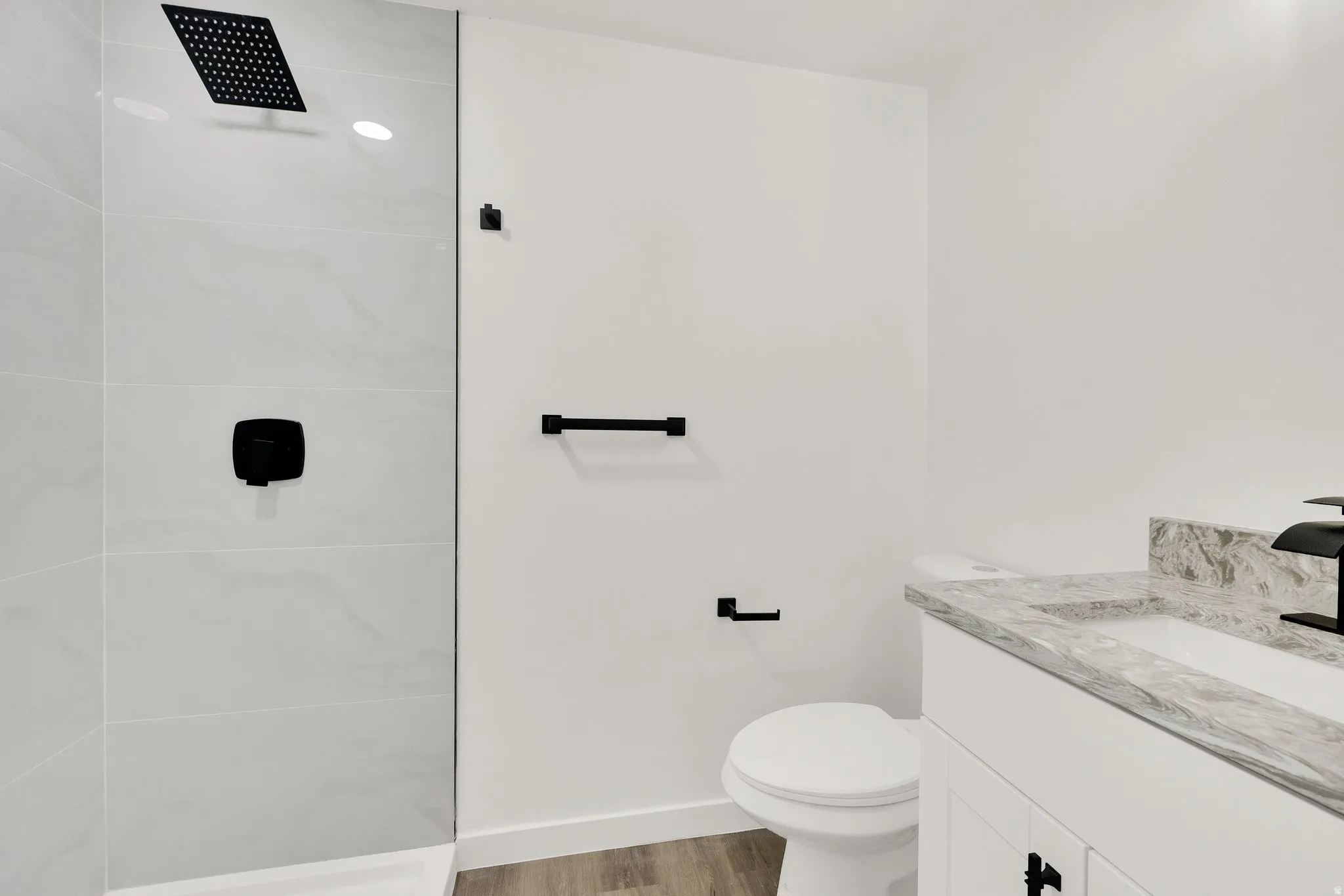 Modern bathroom with a glass-enclosed shower featuring a matte black rainfall showerhead