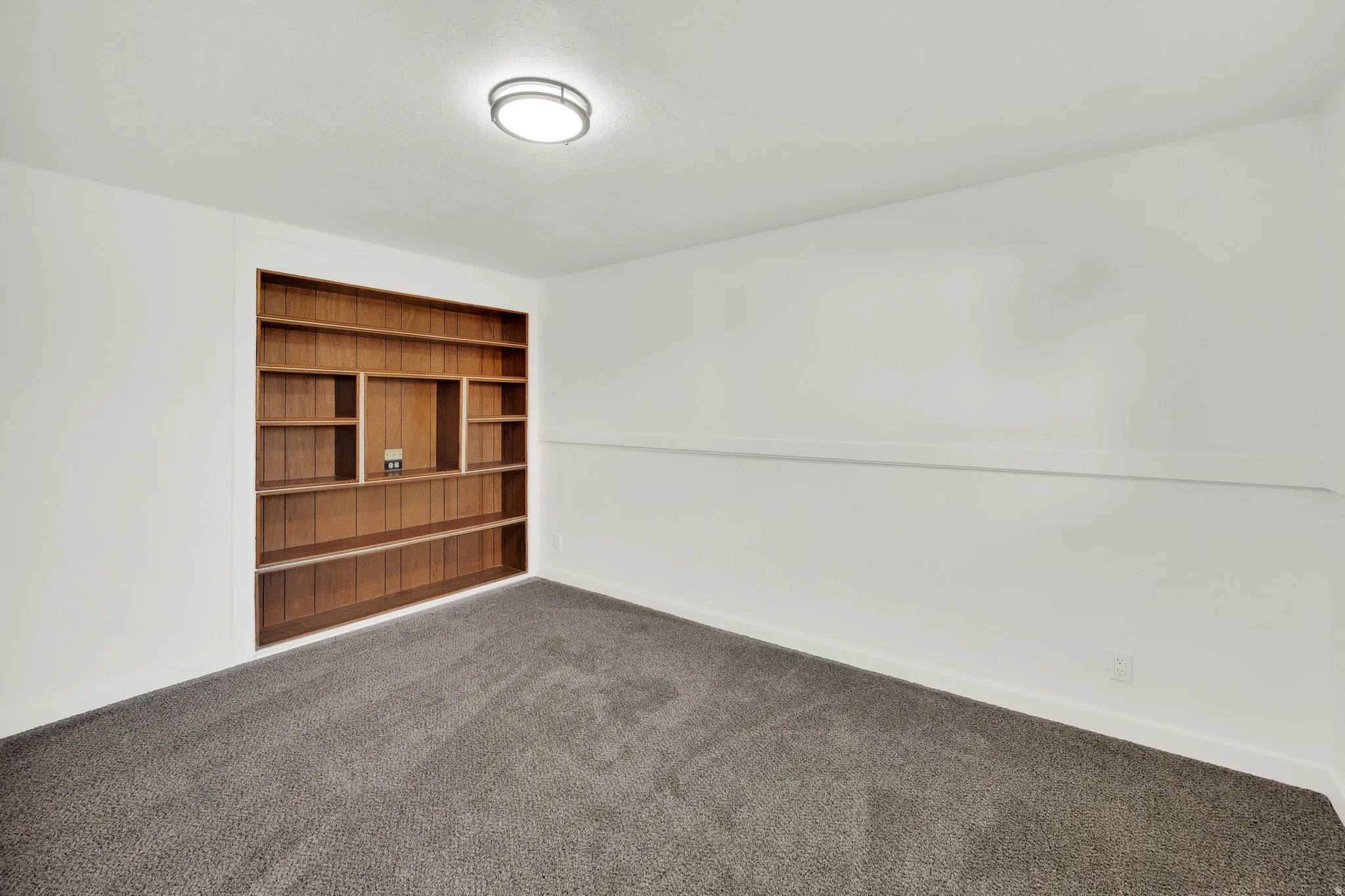 Built-in wood shelving with varied compartment sizes, recessed into a white wall