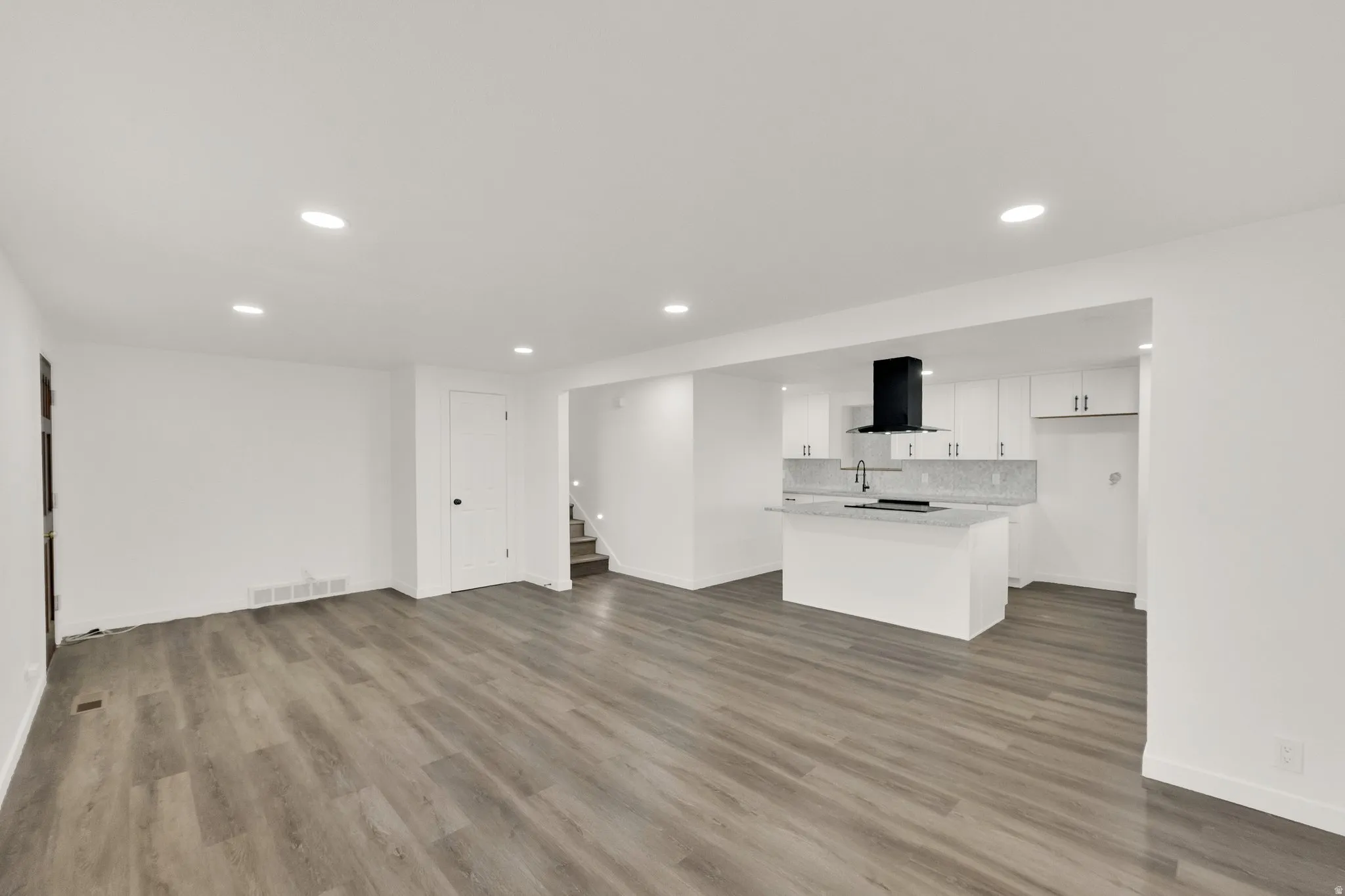 Open-concept interior featuring wood-finish flooring, recessed lighting, and white walls