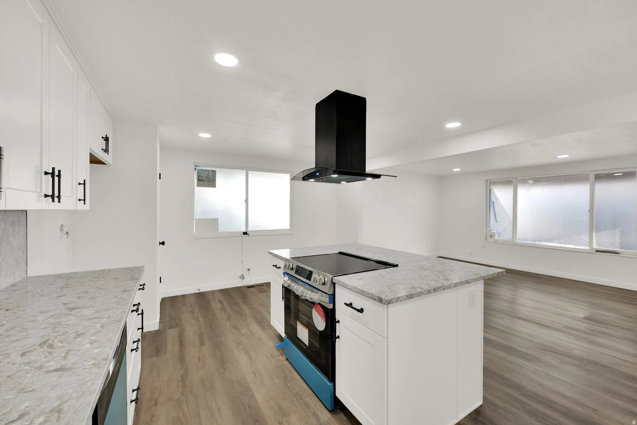 Open-concept kitchen featuring an island range with an overhead vent hood