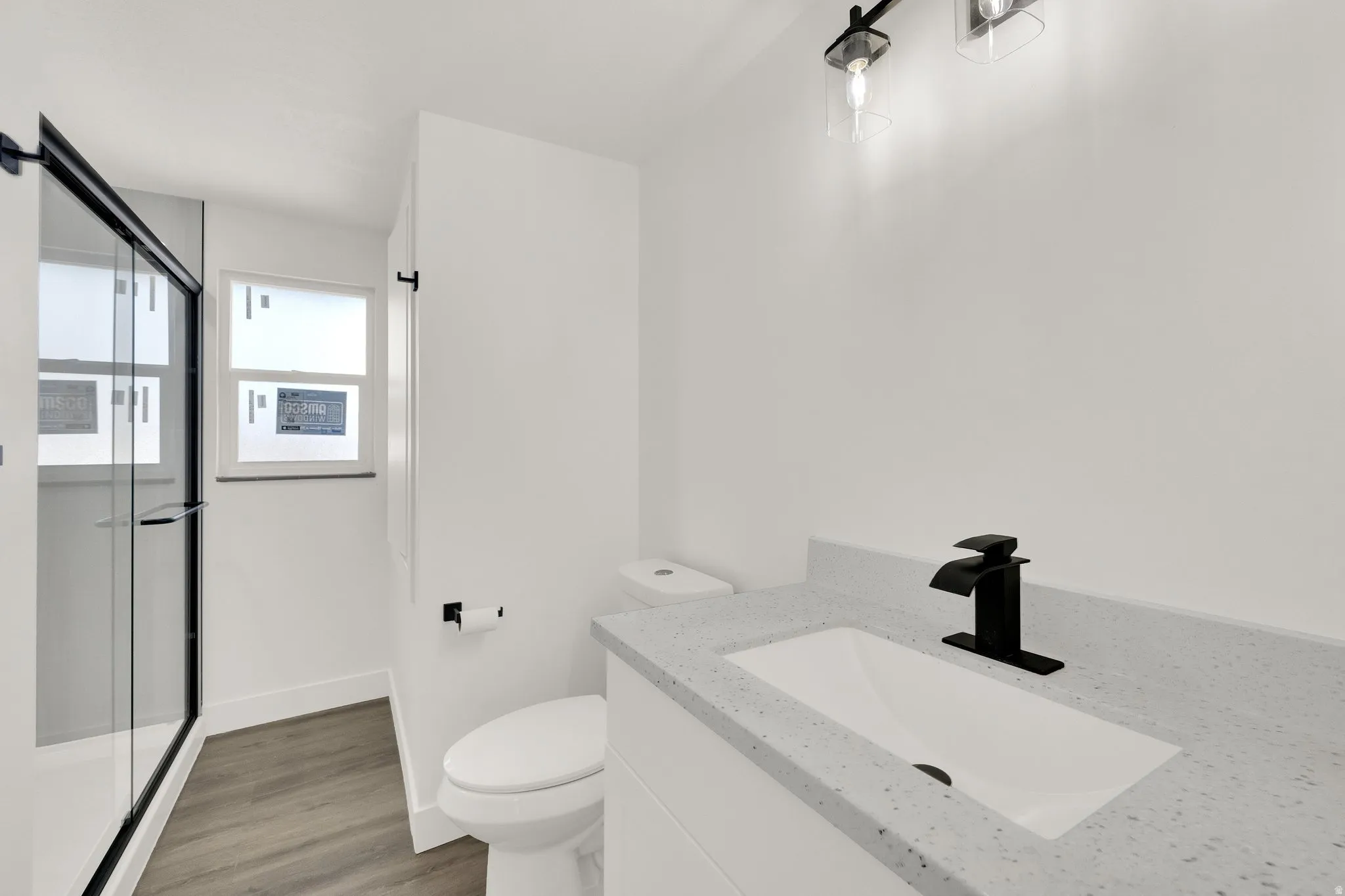Modern bathroom featuring a single vanity with a light speckled countertop, matte black faucet, and under-mount sink