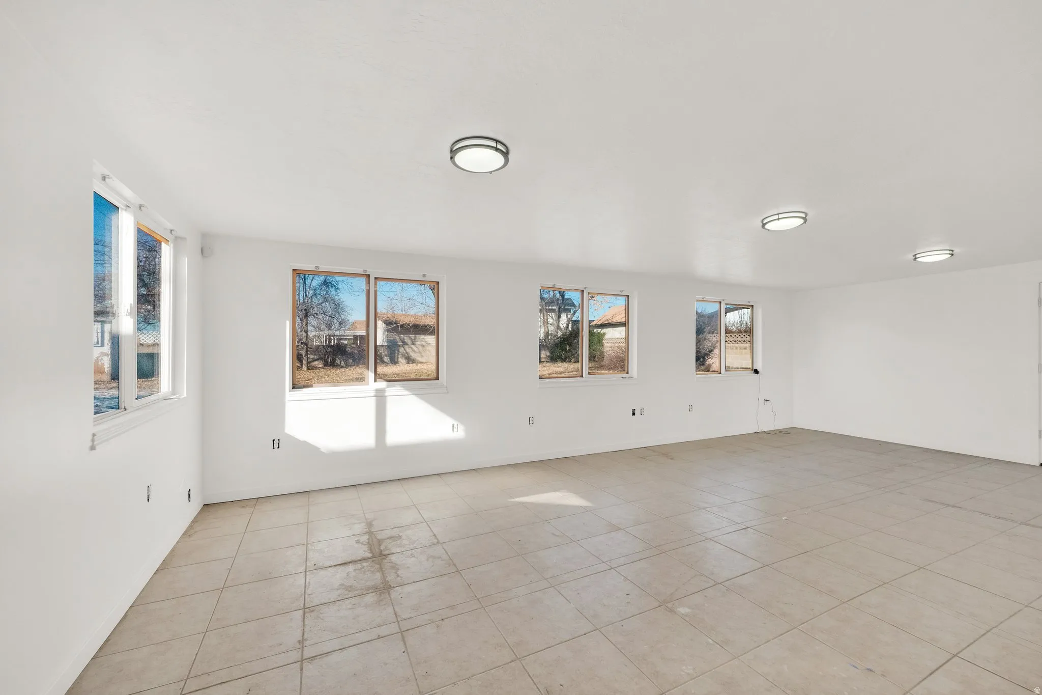 Spacious room featuring tile flooring, multiple windows, and recessed lighting fixtures