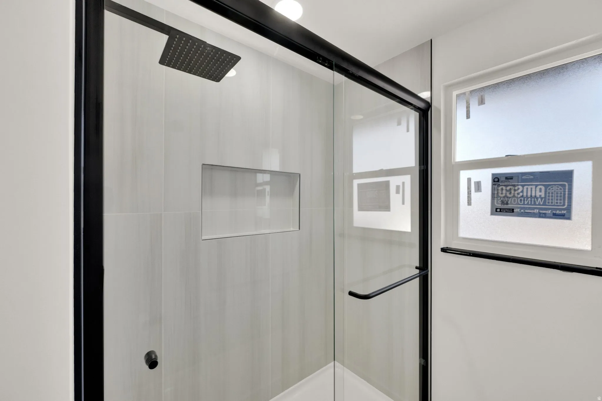 Modern walk-in shower featuring a matte black framed glass enclosure