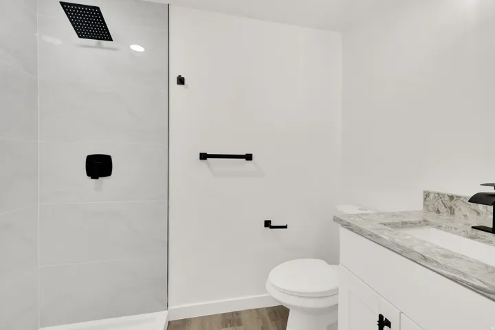 Modern bathroom with a glass-enclosed shower featuring a matte black rainfall showerhead