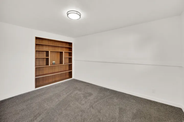 Built-in wood shelving with varied compartment sizes, recessed into a white wall
