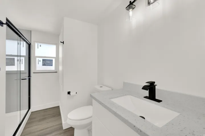 Modern bathroom featuring a single vanity with a light speckled countertop, matte black faucet, and under-mount sink