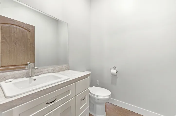Modern bathroom vanity featuring white shaker-style cabinetry, an integrated white sink, and a brushed nickel faucet