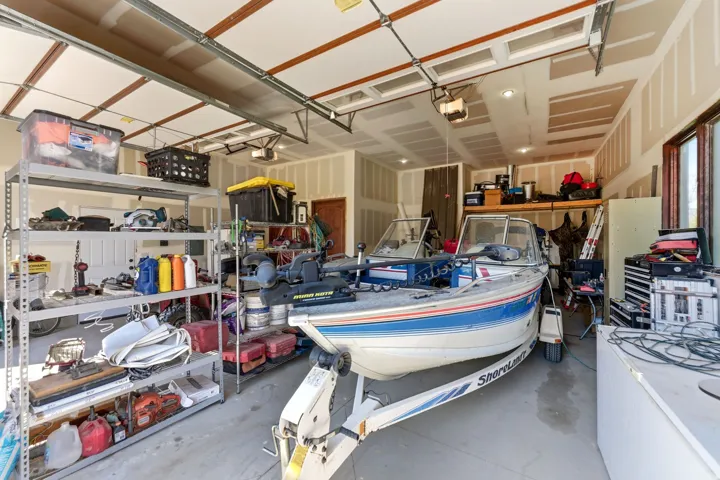 Spacious garage featuring high ceilings, exposed beams, and multiple windows providing natural light