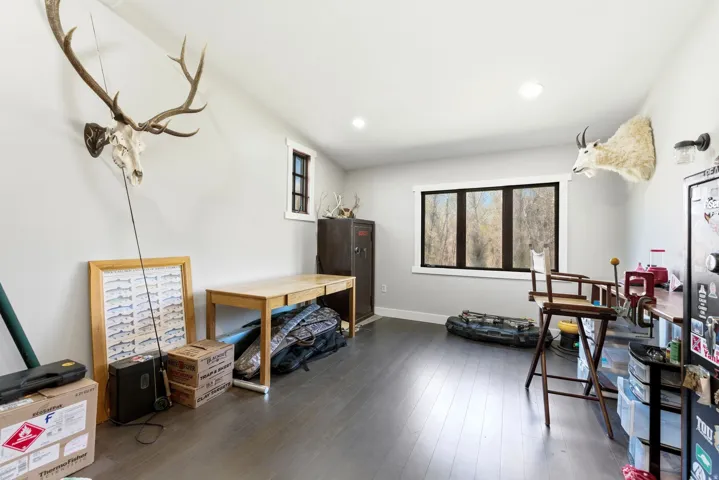 Spacious room with dark wood-finish flooring, recessed lighting, and a large multi-pane window