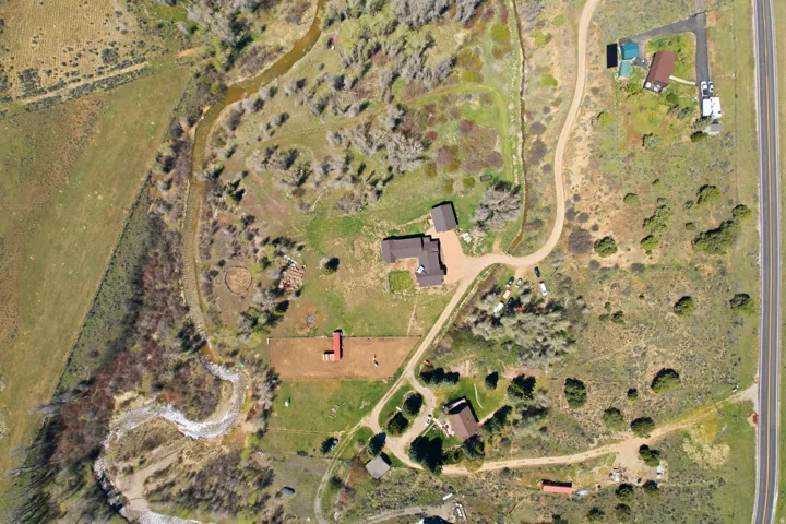 Expansive property featuring a main residence, secondary buildings, and a winding creek
