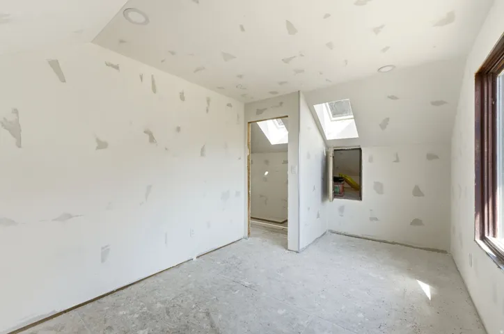 Unfinished interior space featuring a sloped ceiling with two skylights and recessed lighting