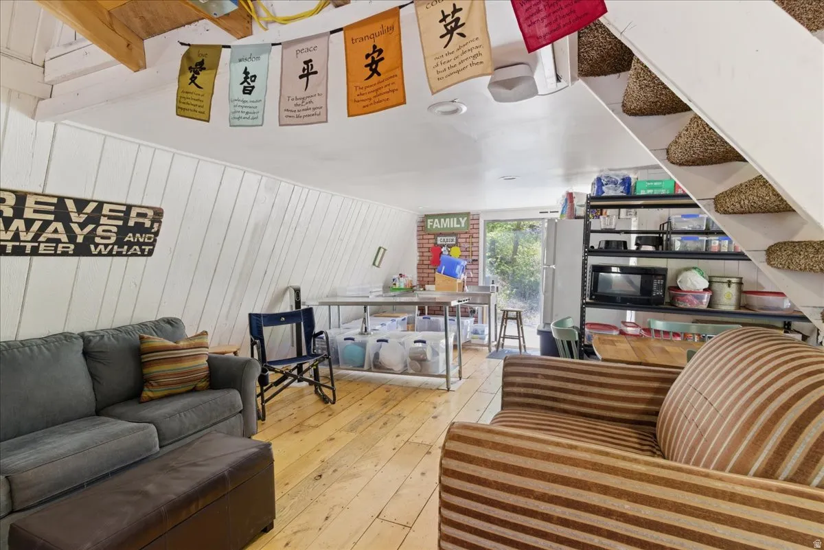 Spacious room with sloped white wood-paneled walls and wood-finish flooring
