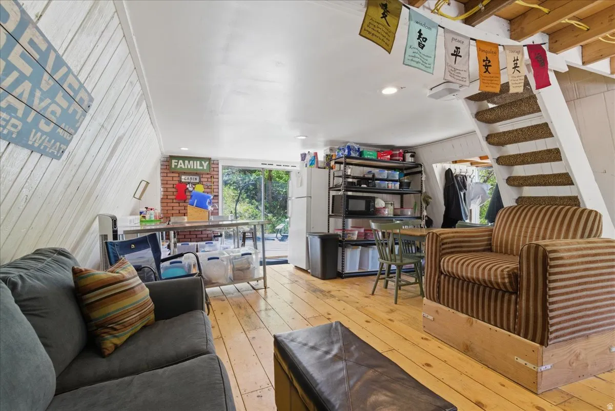 Open-concept room featuring wood-finish flooring, white shiplap walls, a white painted ceiling, and a built-in staircase with carpeted treads
